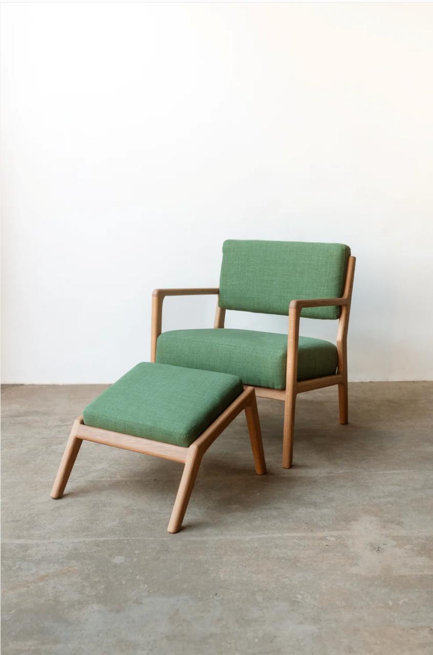 Green armchair with matching ottoman on a concrete floor.