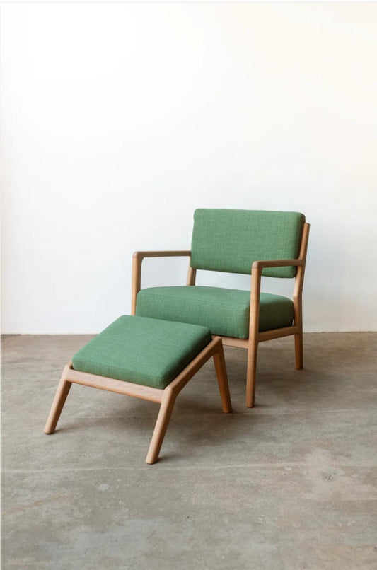 Green armchair with matching ottoman on a concrete floor.